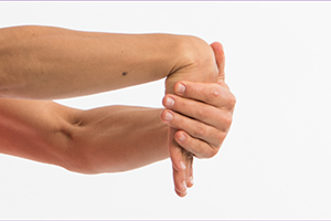 Person gently pressing down with their left hand on top of right hand to flex the wrist.