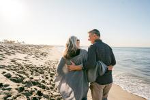 older couple walking on the beach together and smiling