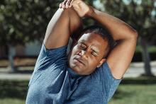 African American man stretching with one arm behind his back.