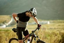 Mature man on mountain bike rubbing a sore lower back.