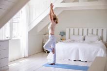 Woman At Home Starting Morning With Yoga Exercises In Bedroom