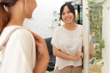 Asian woman welcoming a customer to her store.