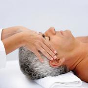An older man receiving a head massage while lying on a massage table