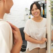 Asian woman welcoming a customer to her store.
